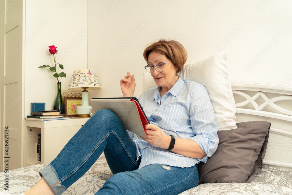 Fototapeta premium An elderly woman happily talking via video communication