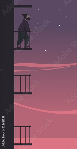 A young man stands on the balcony against the background of the evening sky. Loneliness illustration.