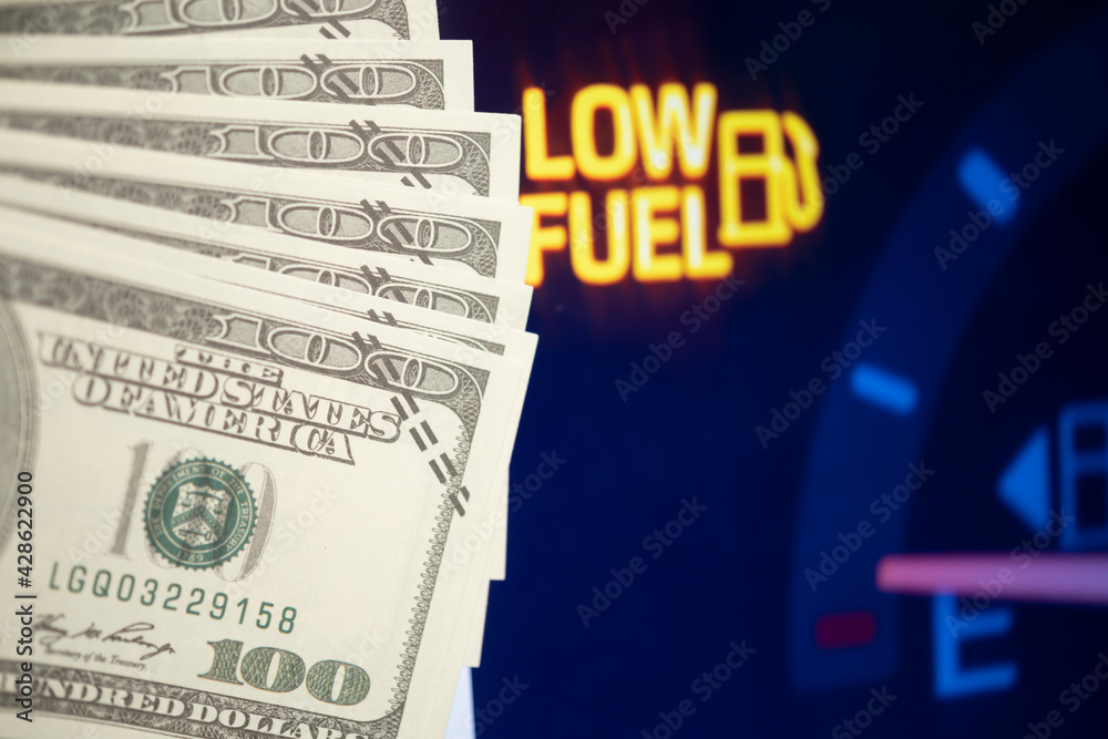 Obraz premium Dollar bills against oil mileage dashboard background