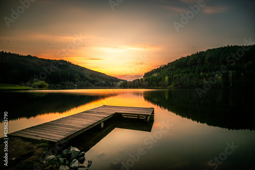 View of a lake in the sunset. A great wooden jetty on a natural lake in the forest. swim and fish photo