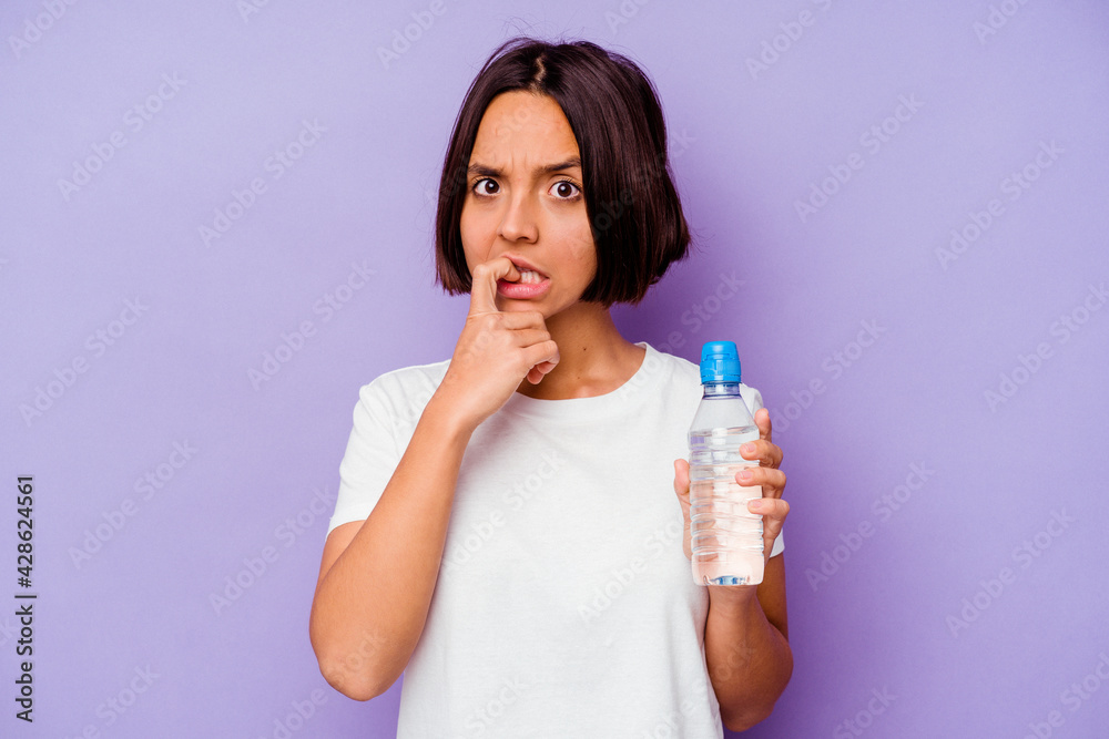 Young mixed race holding a water bottle isolated on purple background biting fingernails, nervous and very anxious. Young mixed race holding a water bottle isolated on purple background biting fingernails, nervous and very anxious.