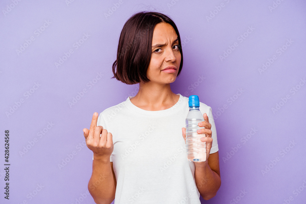 Young mixed race holding a water bottle isolated on purple background pointing with finger at you as if inviting come closer. Young mixed race holding a water bottle isolated on purple background pointing with finger at you as if inviting come closer.