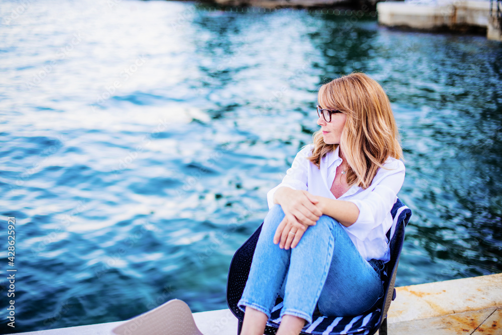Mature woman deep in thought while sitting by the sea