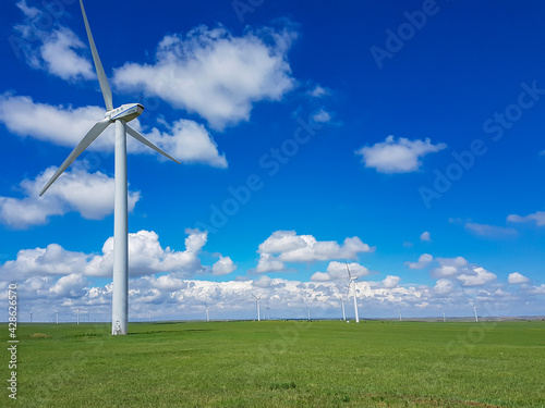 A field of wind turbines build on a vast pasture in Xilinhot in Inner Mongolia. Natural resources energy. Clean energy. Endless grassland. Blue sky with white, thick clouds. Serenity