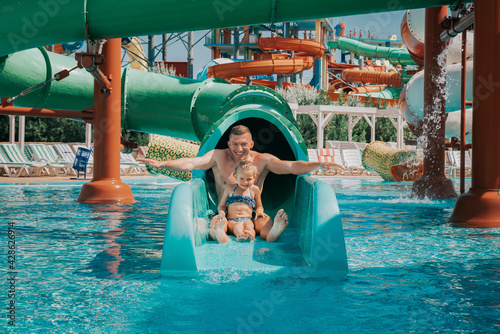 Father playing with his daughter in swimming pool. Funny family weekend. Father and daughter enjoy time together in water park.  photo