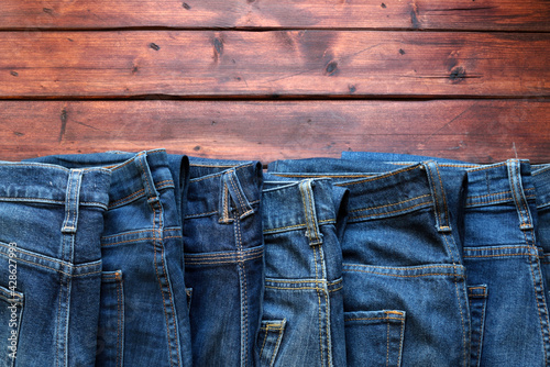 Pila di blue jeans isolato su sfondo di legno. Concetto di abbigliamento di moda. Direttamente sopra.