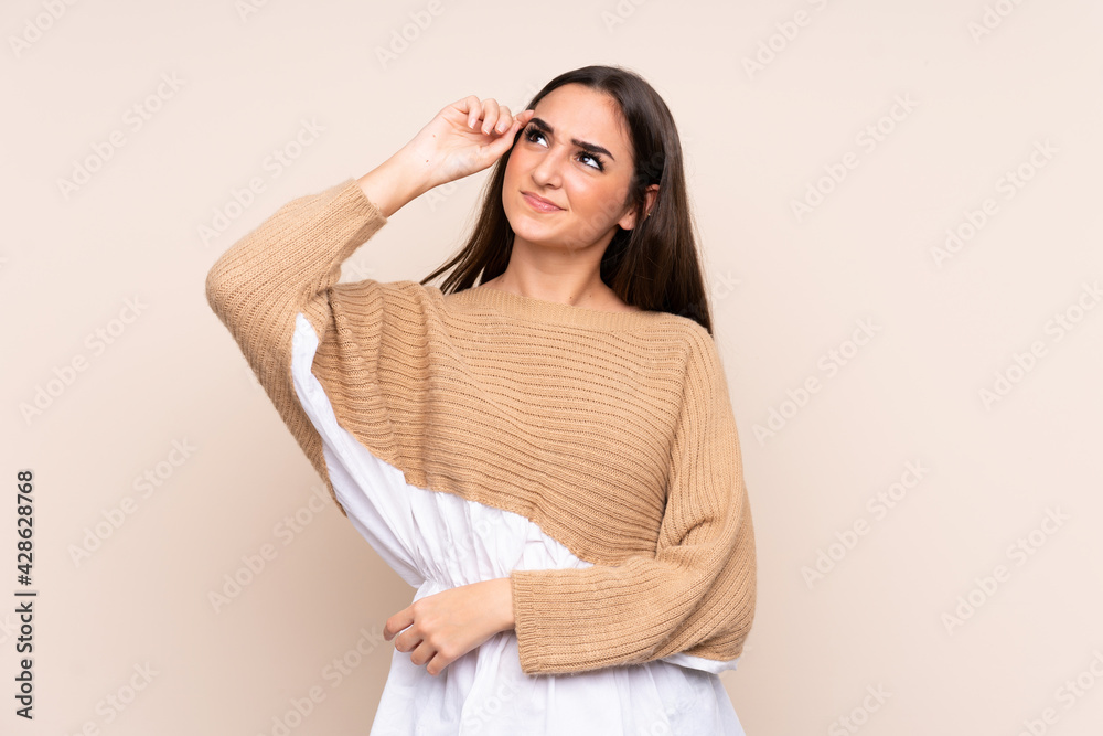 Young caucasian woman isolated on beige background having doubts and with confuse face expression Young caucasian woman isolated on beige background having doubts and with confuse face expression