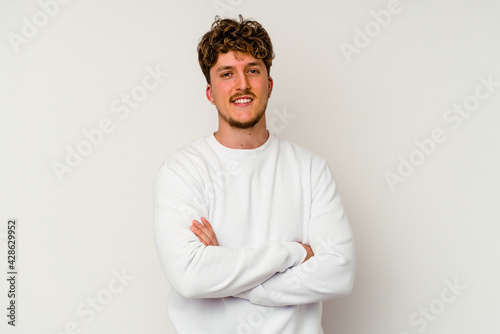 Young caucasian man isolated on white background who feels confident, crossing arms with determination. © Asier