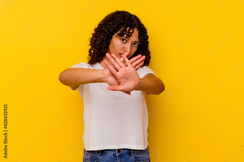 Young mixed race woman isolated on yellow background standing with outstretched hand showing stop sign, preventing you. Young mixed race woman isolated on yellow background standing with outstretched hand showing stop sign, preventing you.