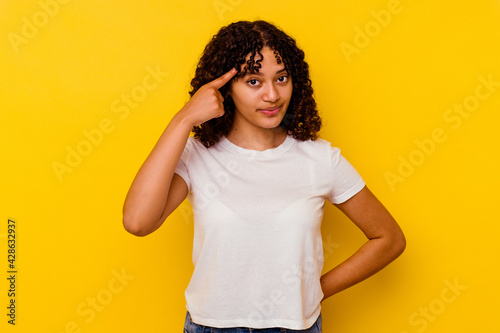 Young mixed race woman isolated on yellow background pointing temple with finger, thinking, focused on a task.