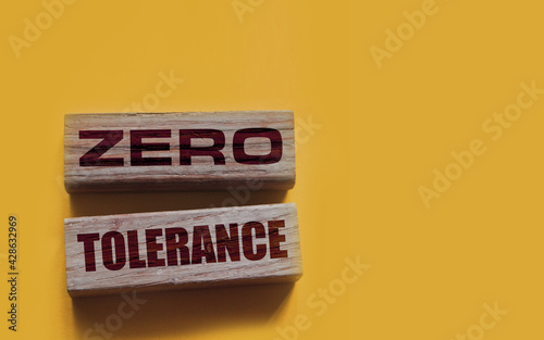Zero tolerance - words from wooden blocks with letters, severely punishing all unacceptable behaviour, zero tolerance concept, yellow background