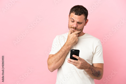 Young Brazilian man isolated on pink background thinking and sending a message © luismolinero