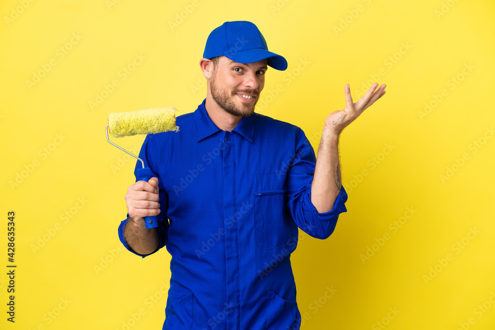 Painter Brazilian man isolated on yellow background extending hands to the side for inviting to come