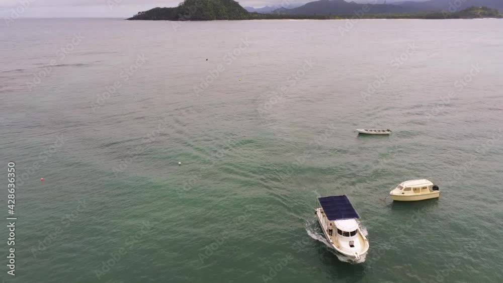 Aerial drone view of a boat arriving at a dock in Ilheu das Rolas, cloudy Sao Tome Aerial drone view of a boat arriving at a dock in Ilheu das Rolas, cloudy Sao Tome