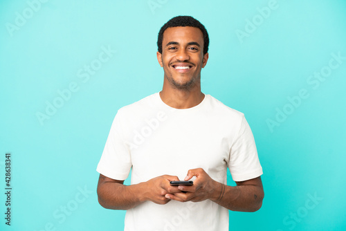 African American handsome man on isolated blue background surprised and sending a message © luismolinero