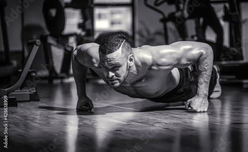 Muscular and strong guy exercising. Slim man doing some push ups a the gym. Man doing push-ups. Black and white