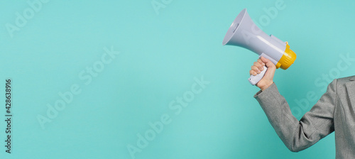 Hand is hold megaphone and wear grey suit on green or mint or Tiffany Blue  background.