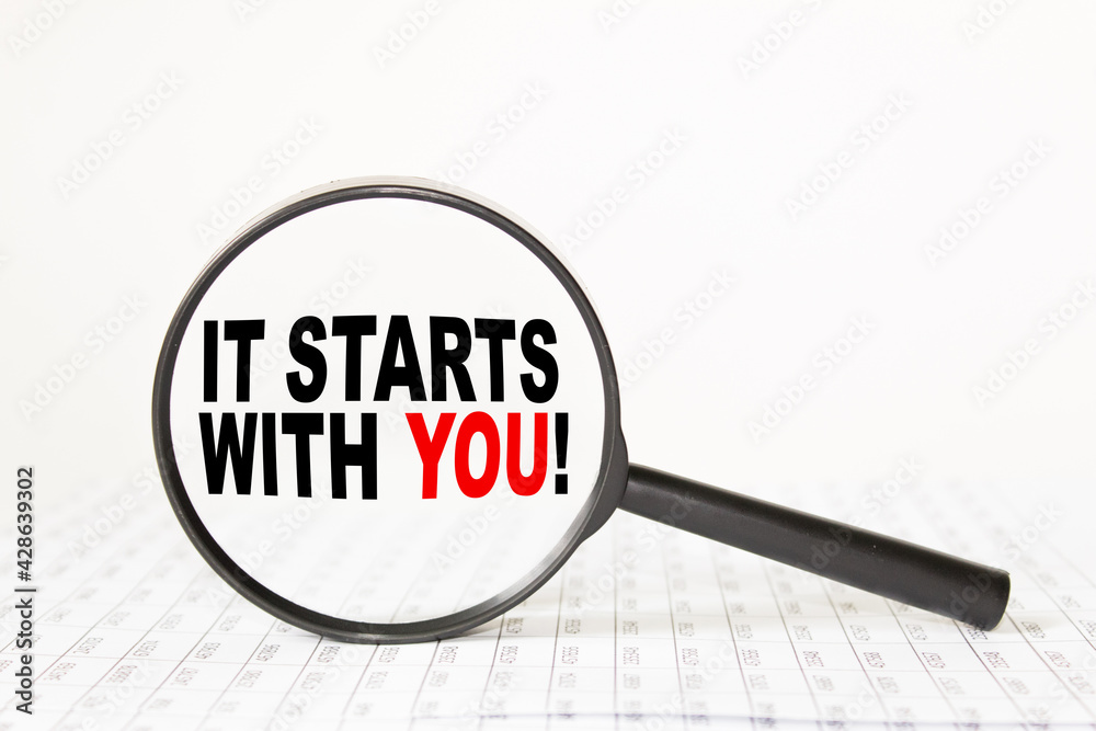 words IT STARTS WITH YOU in a magnifying glass on a white background. business concept words IT STARTS WITH YOU in a magnifying glass on a white background. business concept