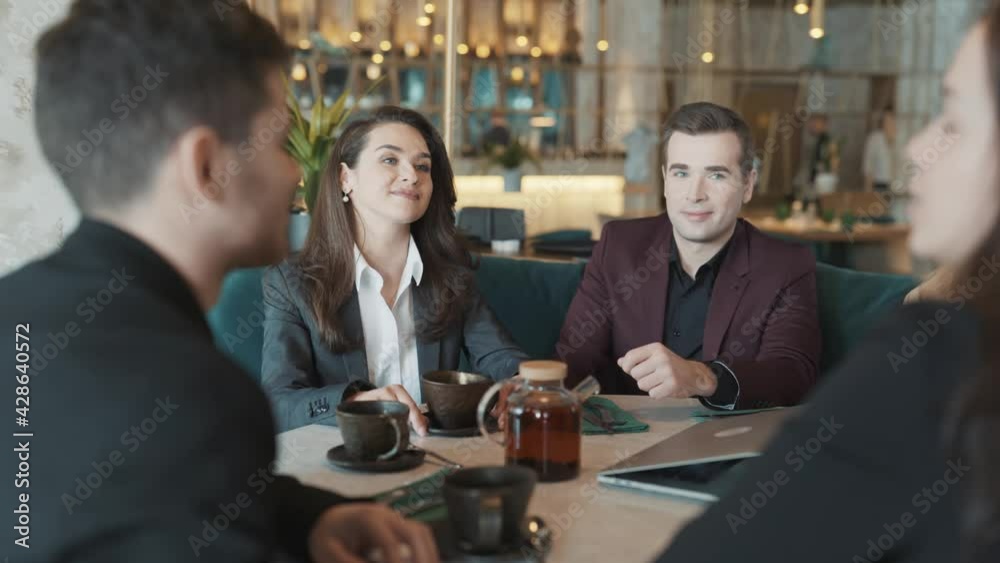 Diverse group of business coworkers sitting at a table in restaurant. Colleagues discussing working situation. Concept of teamwork, leisure, teambuilding. Diverse group of business coworkers sitting at a table in restaurant. Colleagues discussing working situation. Concept of teamwork, leisure, teambuilding.