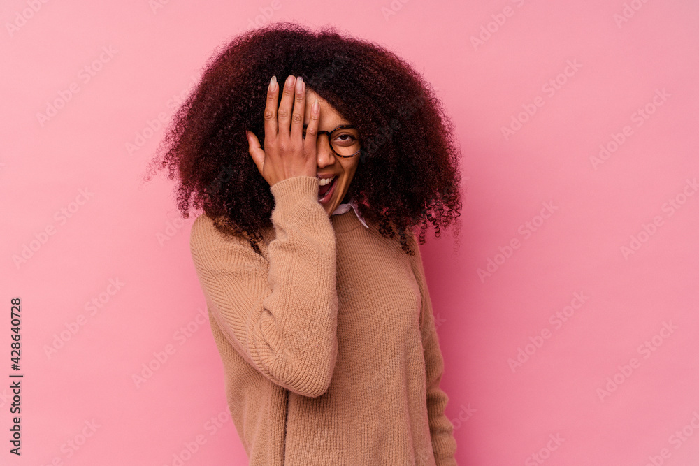 Young african american woman isolated on pink background having fun covering half of face with palm. Young african american woman isolated on pink background having fun covering half of face with palm.