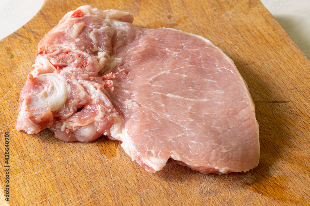 Raw Pork Chops on the wooden cutting board Raw Pork Chops on the wooden cutting board