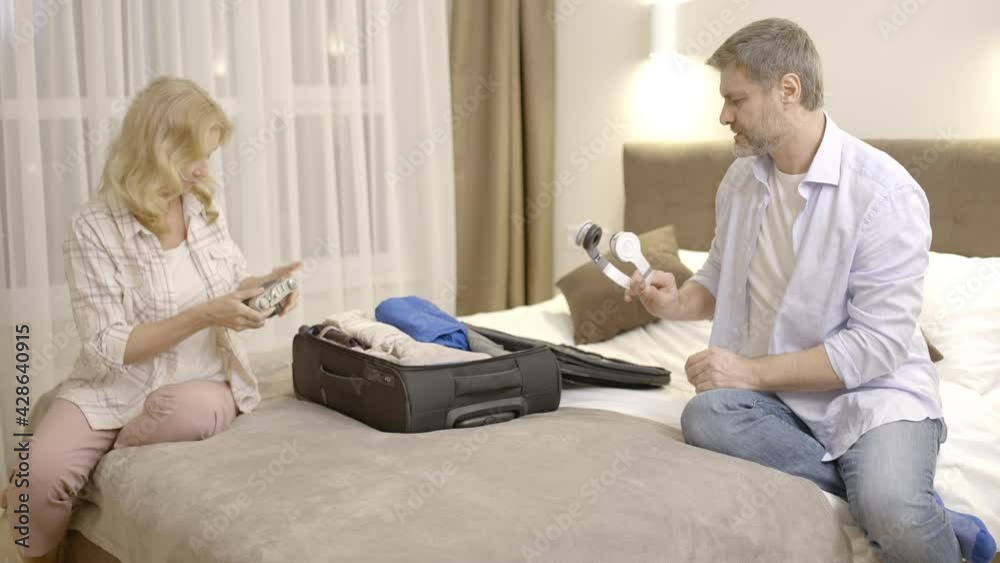 Glad man and woman packing suitcase, preparing for vacation, family travelling