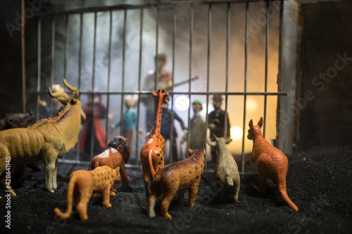 People and animals on opposite sides of the fence concept. Creative decoration with toy figures. Burning colorful background.