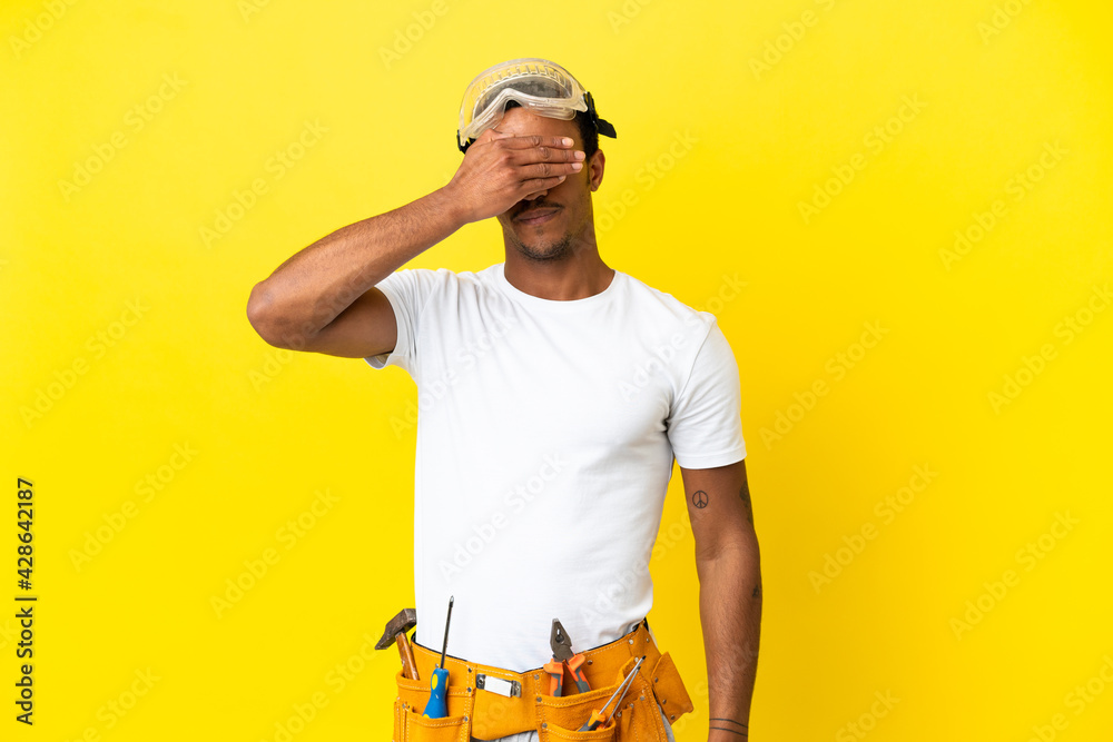 African American electrician man over isolated yellow wall covering eyes by hands. Do not want to see something African American electrician man over isolated yellow wall covering eyes by hands. Do not want to see something