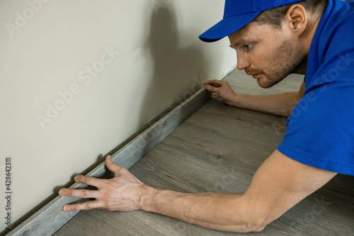 worker installing skirting board, baseboard photo