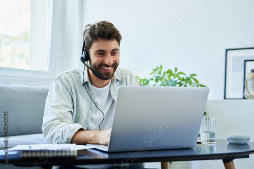 Young man with headset telecommuting photo