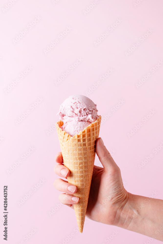 Female hand holding the ice cream, pink background Female hand holding the ice cream, pink background
