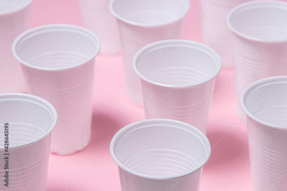 Plastic glasses on a pink background. Disposable tableware. Plastic products. Plastic glasses on a pink background. Disposable tableware. Plastic products.