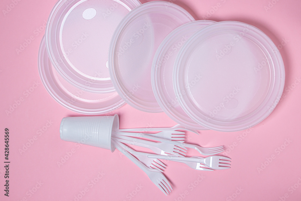 Plastic dishes on a pink background. Disposable tableware. Plastic products. Plastic dishes on a pink background. Disposable tableware. Plastic products.