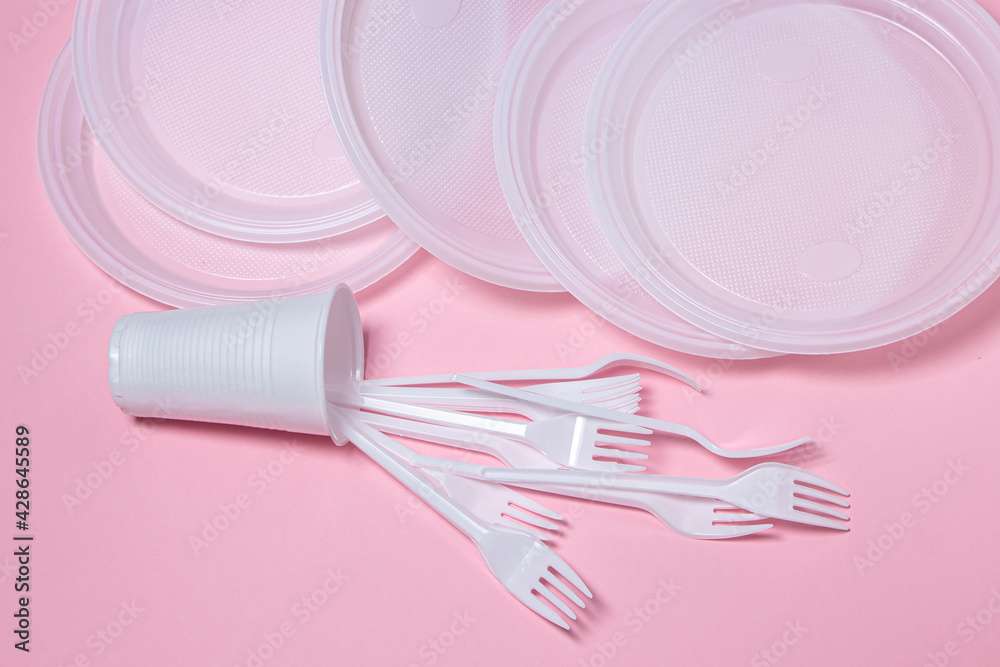 Plastic dishes on a pink background. Disposable tableware. Plastic products. Plastic dishes on a pink background. Disposable tableware. Plastic products.