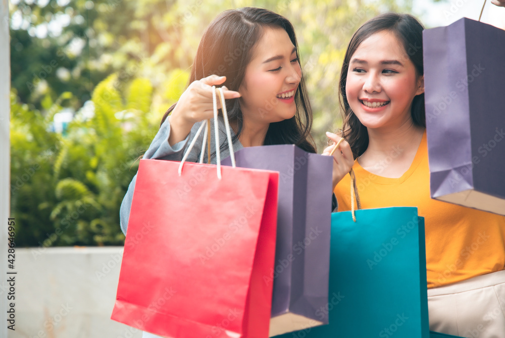  Happy woman with shopping bags enjoying in shopping. Girl holding colour paper bag.Friends walking in shopping mall.time shopping coronavirus crisis or covid19 outbreak.
