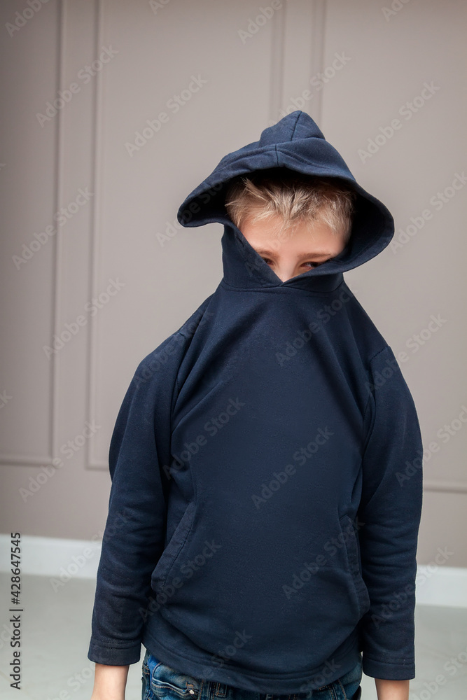 young sad boy in hood looking down and worried of problem at school. Bullying, depression, child protection or loneliness concept young sad boy in hood looking down and worried of problem at school. Bullying, depression, child protection or loneliness concept