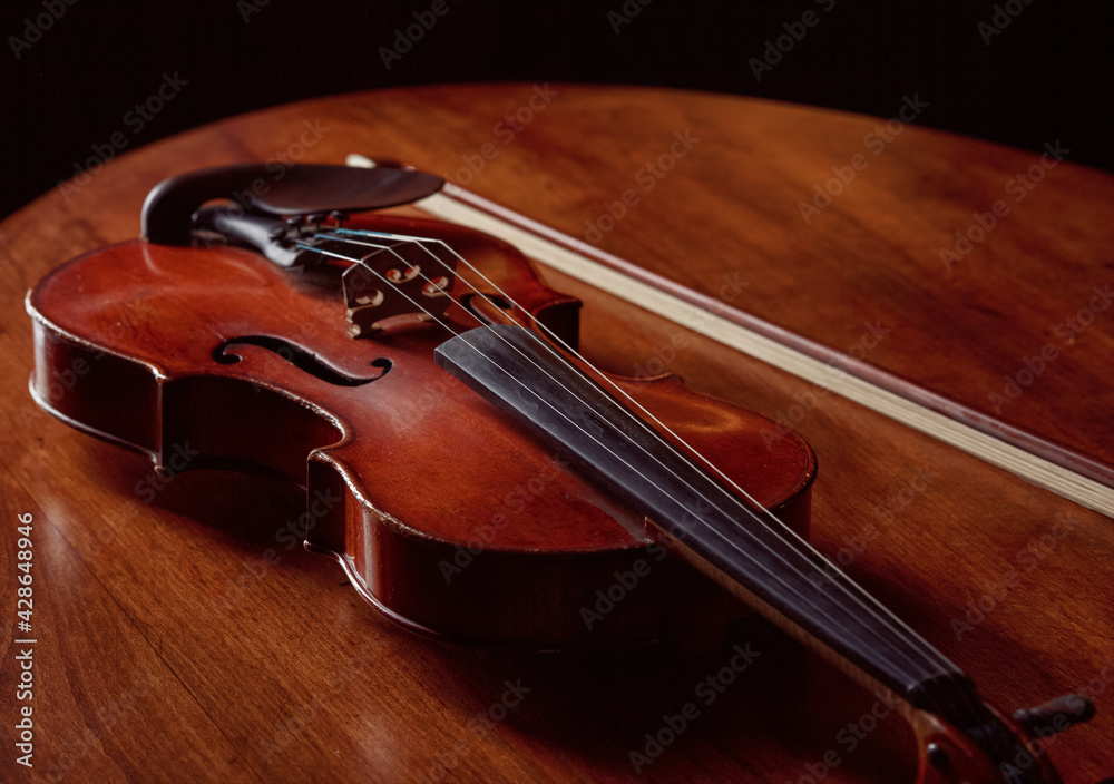 Violin in retro style and bow on wooden table Violin in retro style and bow on wooden table