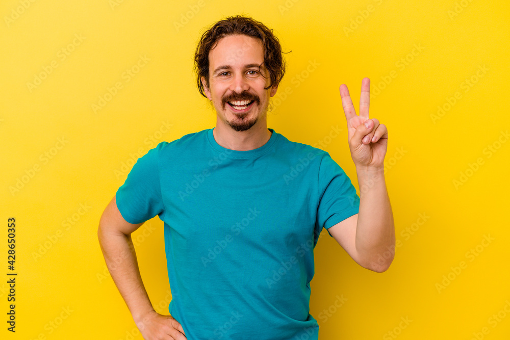 Young caucasian man isolated on yellow background showing number two with fingers.
