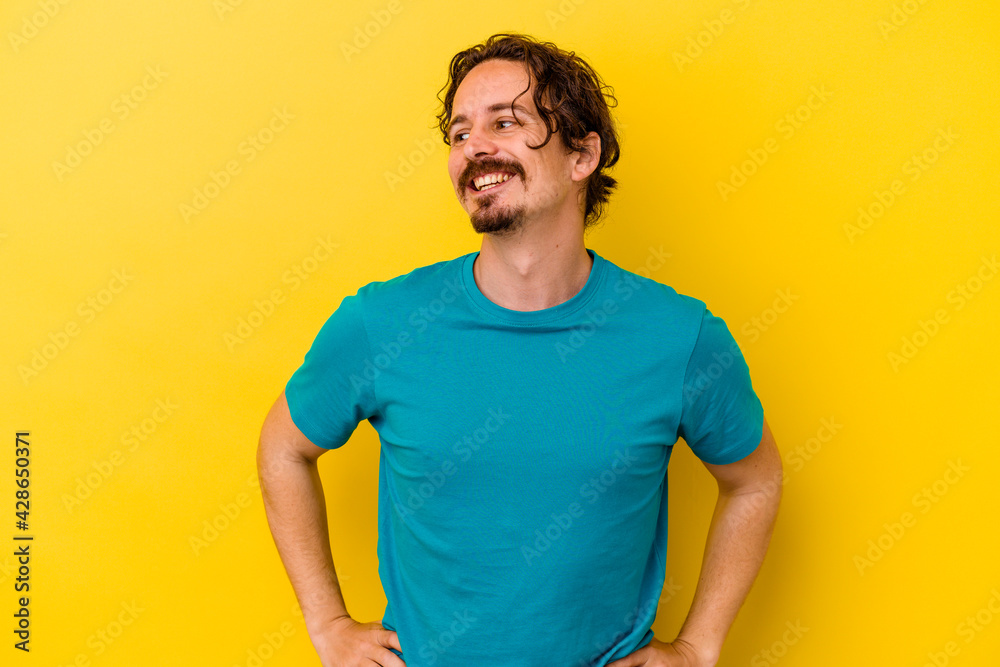 Young caucasian man isolated on yellow background laughs happily and has fun keeping hands on stomach. Young caucasian man isolated on yellow background laughs happily and has fun keeping hands on stomach.