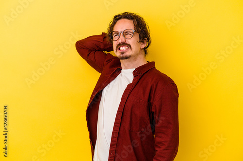 Young caucasian man isolated on yellow background suffering neck pain due to sedentary lifestyle.