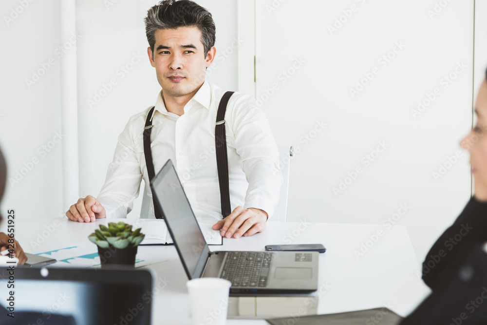 © xartproduction - portrait of asian businessman in a business suit sitting at a table in a meeting