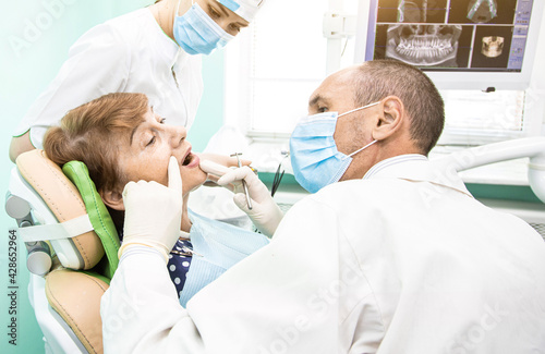Dentistry concept. Professional dental services and modern equipment without pain. The doctor consults and treats an elderly woman.