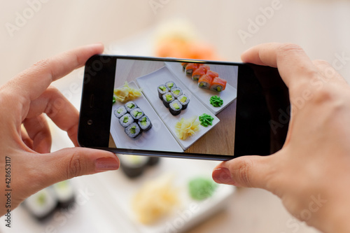 Woman taking photo of tasty sushi set