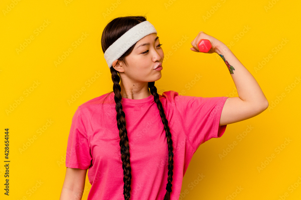 Young sport chinese woman isolated on yellow background