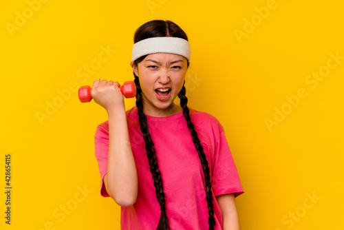 Young sport chinese woman isolated on yellow background