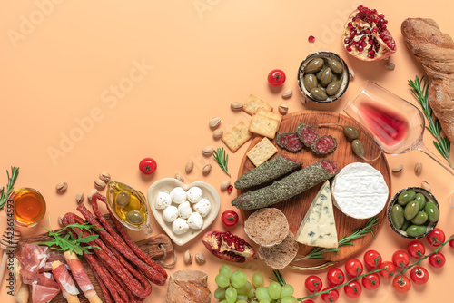 Mediterranean table with various snacks and wine. Traditional Spanish tapas or Italian antipasti on a pastel pink peach background. Top view, flat lay.