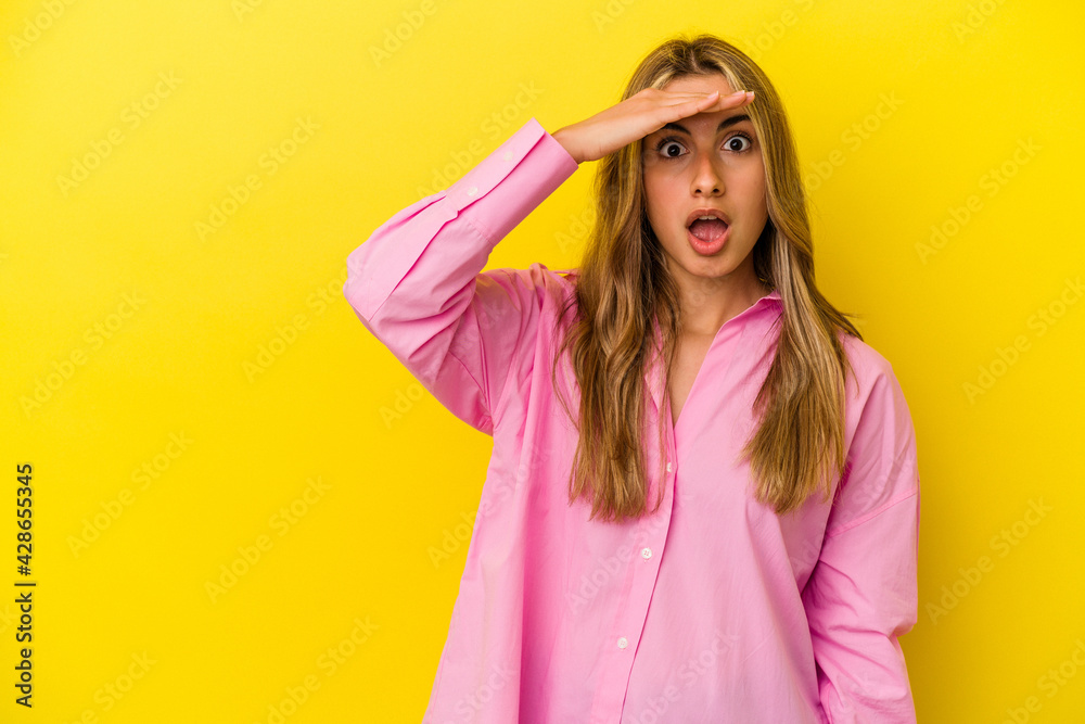 Young blonde caucasian woman isolated on yellow background shouts loud, keeps eyes opened and hands tense. Young blonde caucasian woman isolated on yellow background shouts loud, keeps eyes opened and hands tense.
