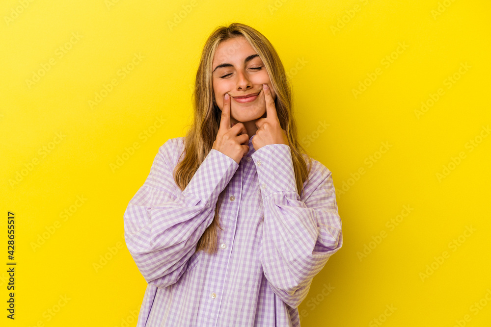 Young blonde caucasian woman isolated on yellow background doubting between two options. Young blonde caucasian woman isolated on yellow background doubting between two options.
