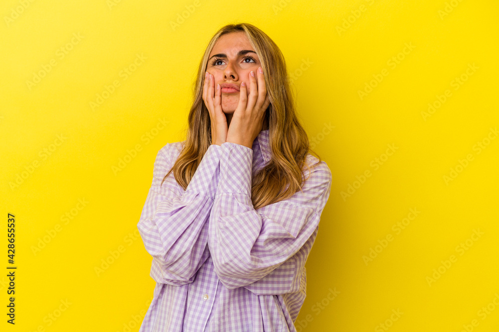 Young blonde caucasian woman isolated on yellow background whining and crying disconsolately. Young blonde caucasian woman isolated on yellow background whining and crying disconsolately.