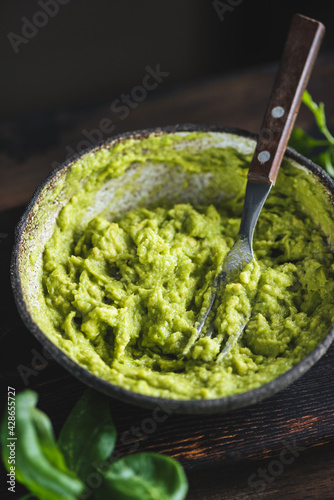 Mashed avocado sauce in a bowl on dark wooden table background